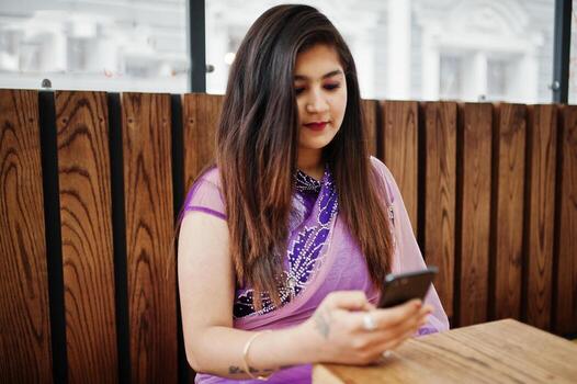 files/indian-hindu-girl-at-traditional-violet-saree-sitting-at-cafe-table-with-mobile-phone-at-hands-photo.jpg